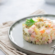 Russian salad Olivier with mayonnaise served in culinary ring. Russian salad Olivier with mayonnaise served in culinary ring on plate. Light background.